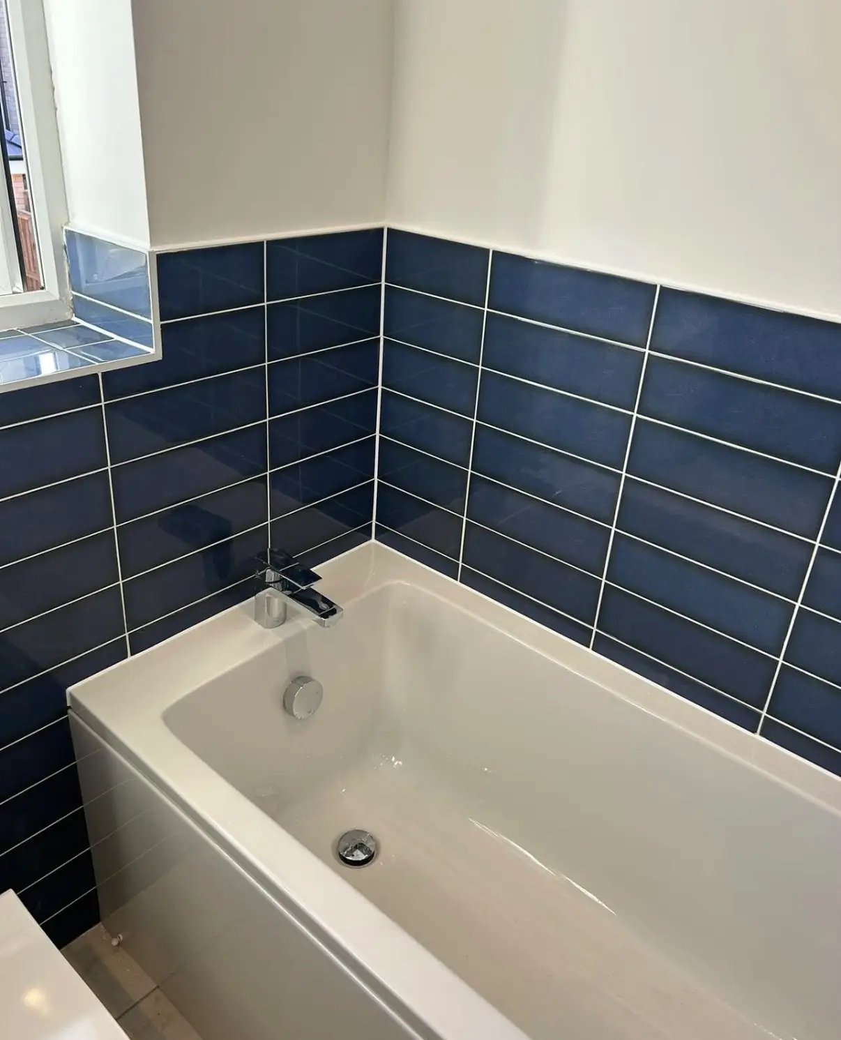 Bath meeting a tiled wall with a clean sealant line